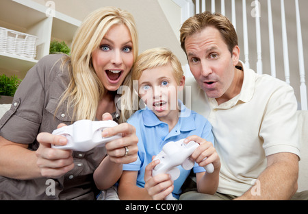 Jeune famille, mère père et fils, parents et enfant, s'amusant à jouer les jeux de console vidéo ensemble. Banque D'Images