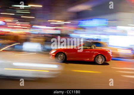 Voiture sport rouge à la croisée des chemins. Rue de Manhattan dans la nuit. Banque D'Images