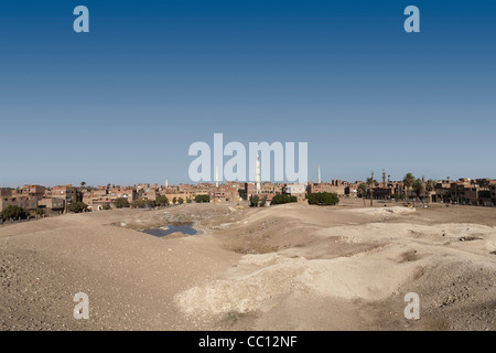 Les ruines de l'enceinte des murs et mound et moderne village en arrière-plan de Kom el Sultan à Abydos Moyenne Égypte Banque D'Images