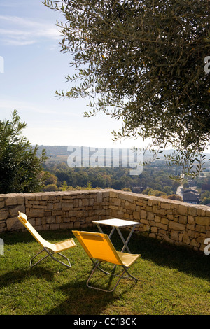 Chaises longues sous un olivier dans Vezenobres Languedoc-Roussillon France Banque D'Images