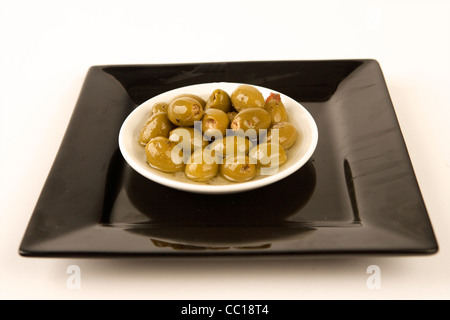 Olives farcies en saumure en plaque blanche avec fond blanc. Banque D'Images