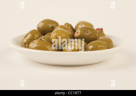 Olives farcies en saumure en plaque blanche avec fond blanc. Banque D'Images