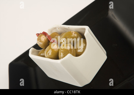 Olives farcies en saumure en plaque blanche avec fond blanc. Banque D'Images