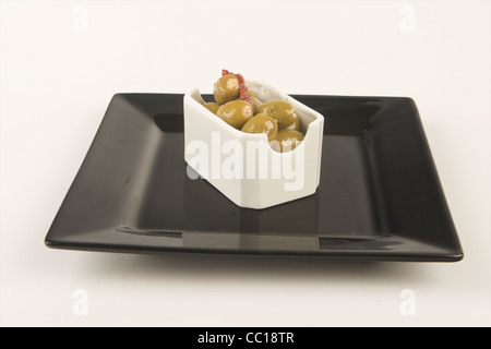 Olives farcies en saumure en plaque blanche avec fond blanc. Banque D'Images