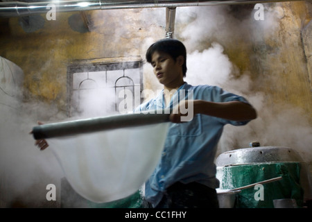 Un homme fait des nouilles de riz fraîches (Banh pho tuoi) pour le plat populaire, Pho au Ba Ngoan factory à Hanoi, Vietnam Banque D'Images