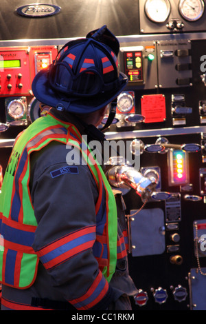 Un pompier aux commandes d'un camion de pompage Banque D'Images