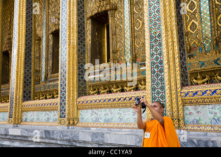 Un moine de prendre une photo en face de l'architecture de Wat Phra Kaew, également connu sous le Temple du Bouddha d'Émeraude. Bangkok, Banque D'Images