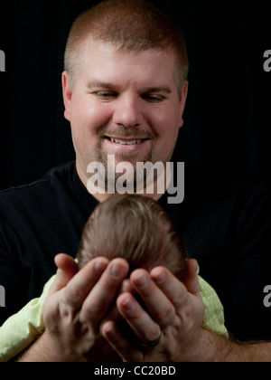 Papa est en tenant son nouveau-né fille et souriant à son amour. Banque D'Images