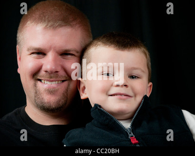 Papa et son fils qui a 4 ans sur un fond noir. Fils est affectueusement appuyé contre son père Banque D'Images