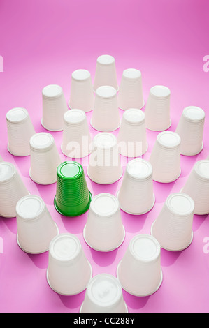 Une tasse en plastique vert parmi un groupe de gobelets en plastique blanc Banque D'Images