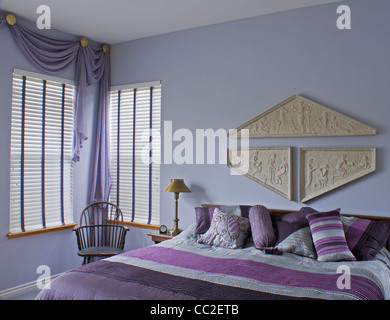 Chambre Prune violet montrant l'intérieur lit, fenêtres, murs, rideaux, président. Banque D'Images