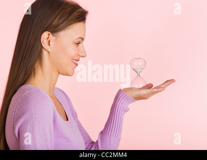 Studio shot of woman holding petit sablier Banque D'Images