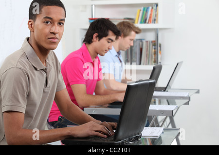 Les jeunes hommes qui travaillent sur leur affectation dans un laboratoire informatique Banque D'Images