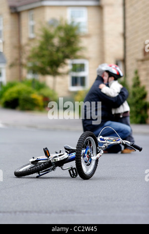 Enfant de tomber de vélo et d'être réconfortés par parent. Banque D'Images