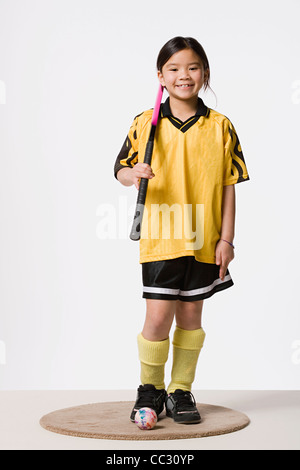 Portrait of smiling girl (8-9) wearing costume de hockey sur gazon, studio shot Banque D'Images