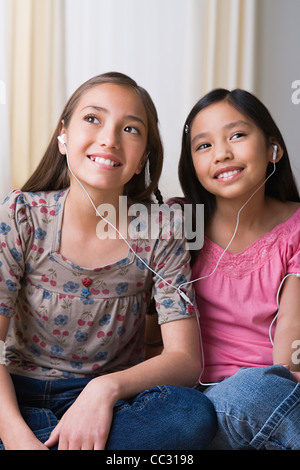 USA, Californie, Los Angeles, Sœurs (8-9, 10-11) listening to music on headphones ensemble Banque D'Images