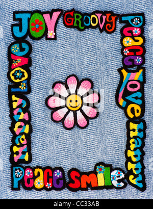 Fer à repasser la broderie sur des parcelles d'amour, de paix, multicolore mots heureux avec un smiley fleur sur un fond jean denim Banque D'Images