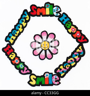 Fer à repasser la broderie sur des parcelles d'heureux et sourire multicolore mots avec un smiley fleur sur fond blanc Banque D'Images
