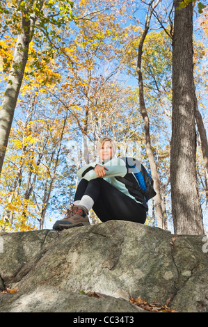 USA (New Jersey), Female hiker resting on rock in forest Banque D'Images