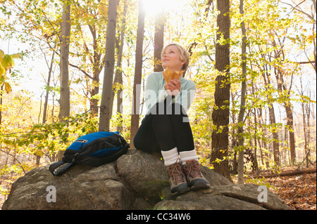 USA (New Jersey), Female hiker resting on rock in forest Banque D'Images