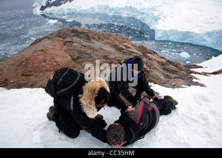 Un chirurgien traumatologie s'occupe d'un alpiniste tombé sur la face de la montagne de Neko Harbour, l'Antarctique Banque D'Images