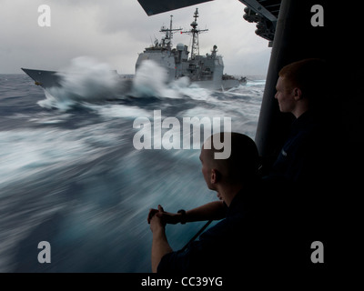 La classe Ticonderoga croiseur lance-missiles USS Bunker Hill (CG 52) prendre sur le carburant dans une mer formée au cours d'un ravitaillement en mer Banque D'Images