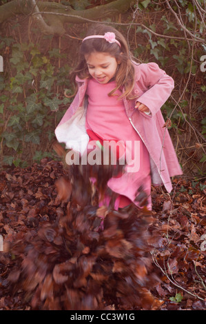 Enfant, petite fille de cinq ans, avoir du plaisir en dehors des coups de piles de feuilles d'automne. Banque D'Images