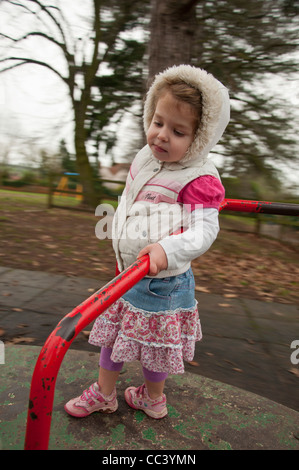 Jeune fille jouant sur le rond-point de jeux Banque D'Images