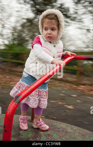 Jeune fille 3 ans jouant sur aire de rond-point Banque D'Images