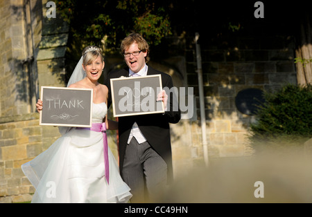Une Bride and Groom holding merci tableau signe le jour de leur mariage. Banque D'Images