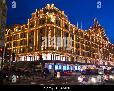 Harrods Noël au crépuscule avec des lumières de Noël et les acheteurs de voitures taxis pour Knightsbridge Londres SW1 Banque D'Images