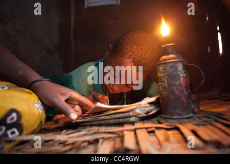 Les études d'un étudiant par la lumière d'une lampe à kérosène à Masaka, en Ouganda, en Afrique de l'Est. Banque D'Images