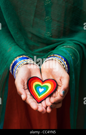 Les filles indiennes mains tenant un fer à repasser sur la broderie d'un patch coeur amour multicolores. L'Inde Banque D'Images