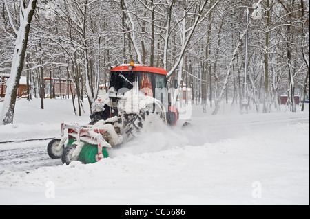 Déneigement d'hiver d'un petit tracteur dans le parc Banque D'Images