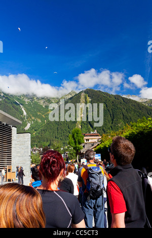 Les touristes font la queue pour le téléphérique au sommet du Mont Blanc, Chamonix alpes avec parapentes dans le ciel au-dessus Banque D'Images