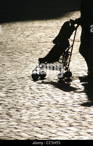 Femme de l'ombre des jambes pieds poussant dans la pram bébé soleil en rue en ville Banque D'Images