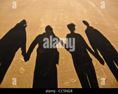 Ombre de family on beach holding hands Banque D'Images