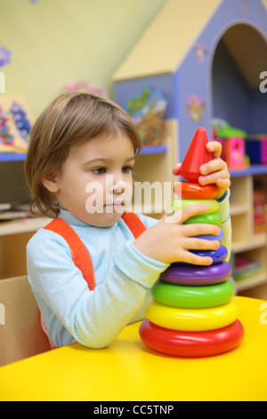 Petite fille joue dans l'école maternelle avec pyramide en plastique Banque D'Images