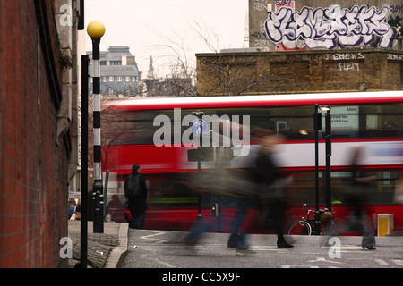 Tir de vitesse lente de personnes traversant un passage clouté à Waterloo, Londres, et un bus passant à l'arrière-plan Banque D'Images