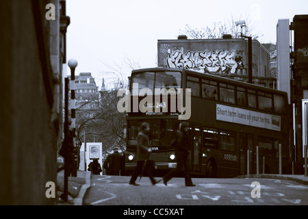 Les personnes qui traversent un passage piéton à Waterloo, Londres, et un bus de Londres rouge approchant, photographié en sépia Banque D'Images