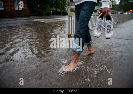 Il y a un passant par le biais d'un chaussures de la ville inondée après de fortes pluies a inondé la ville Banque D'Images