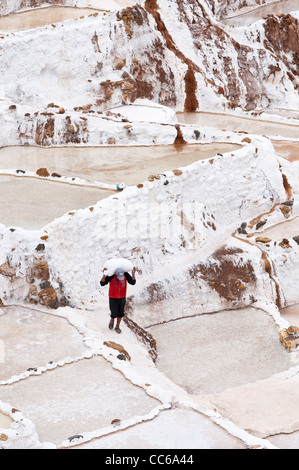 Les hommes travailleurs Inca homme sac sacs de transport à Salinas de Maras les étangs d'eau salée avec terrasse panoramique, terrasses des mines Mines Vallée Sacrée, le Pérou. Banque D'Images