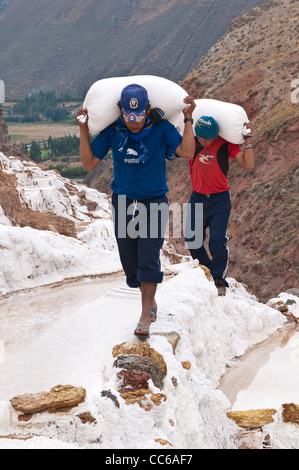 Les travailleurs hommes Inca sac sacs de transport à Salinas de Maras les étangs d'eau salée avec terrasse panoramique, terrasses des mines Mines Vallée Sacrée, le Pérou. Banque D'Images