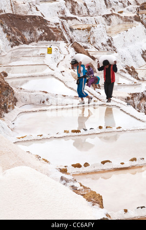 Les travailleurs hommes Inca transportant des sacs de sel sac à Salinas de Maras les étangs d'eau salée avec terrasse panoramique, terrasses des mines Mines Vallée Sacrée, le Pérou. Banque D'Images
