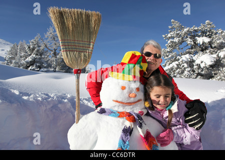 Petite fille et grand-père avec leur snowman Banque D'Images