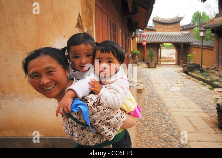 Deux filles sur le dos de sa mère, Shaxi, ville ancienne, Dali, Yunnan, Chine Banque D'Images