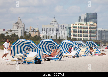 Les touristes avec parasol à la plage avec l'horizon de South Beach, Miami, Floride, USA Banque D'Images