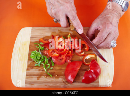 Senior woman mains hacher les légumes sur une planche en bois dans la cuisine Banque D'Images