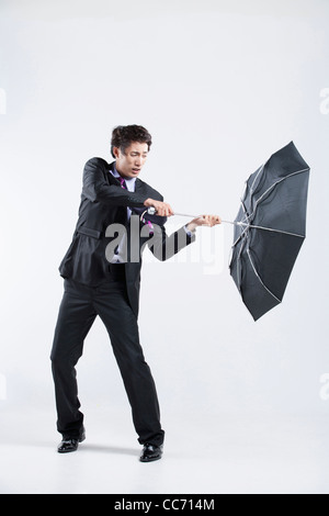 Un homme frappé par le vent fort avec un parapluie à l'envers Banque D'Images