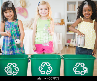 Mettre les enfants matières recyclables dans les bacs de recyclage Banque D'Images